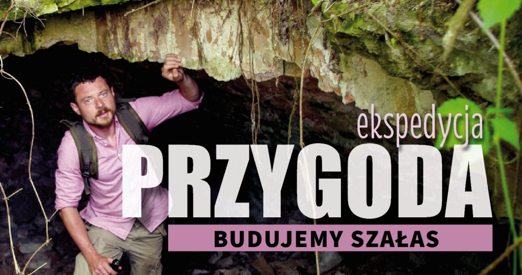 Zdjęcie prowadzącego Łukasza Tuleja przy skale/starym murze. Ma na sobie plecak i różową koszulę, patrzy w kamerę. W prawym dolnym rogu napis: Ekspedycja przygoda Budujemy szałas