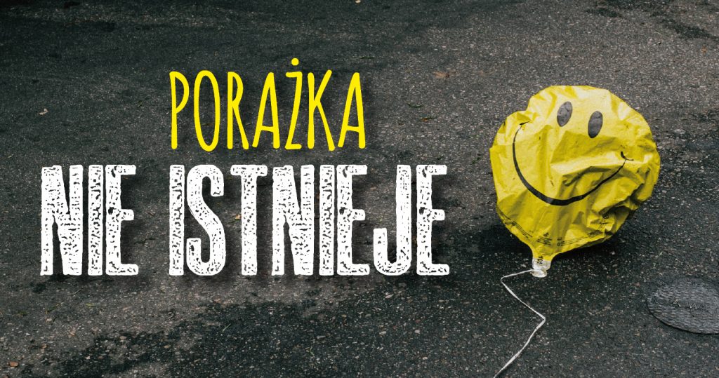 na zdjęciu znajduje się poniszczony, żółty balon z uśmiechniętą buzią, który leży na chodniku. Napis na środku: Porażka nie istnieje