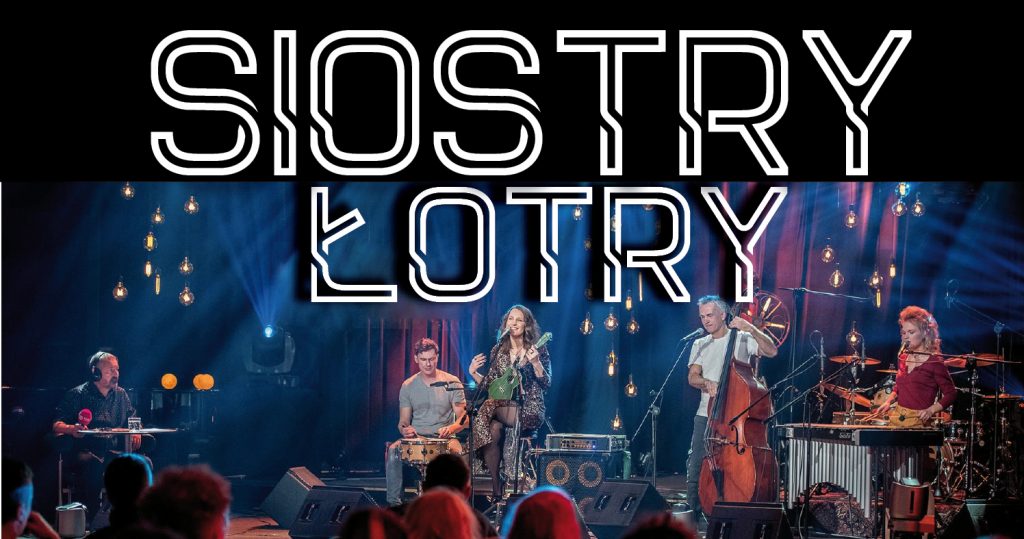 Zdjęcie przedstawia zespół muzyczny "Siostry Łotry" w trakcie koncertu. Na górze zdjęcia znajduje się bardzo duży napis "Siostry Łotry"