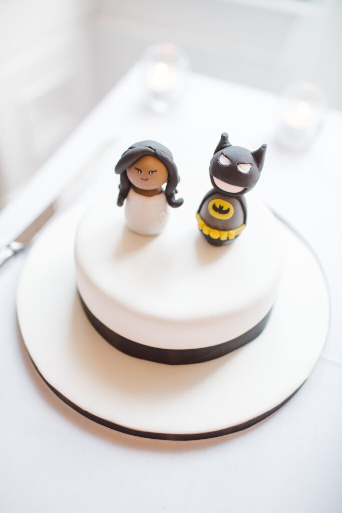Figurki na torcie zrobione z masy cukrowej przedstawiające kobietę w białej sukni oraz mężczyznę przebranego za Batmana.